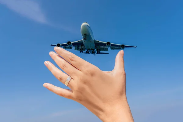 Mão feminina com um anel com um avião desenhado segurando um avião voando no céu. Viajando em um conceito de avião. Espaço de texto. Paraíso impressionante. Praia quente Mai Khao. Paisagem incrível FORMATO VERTICAL — Fotografia de Stock