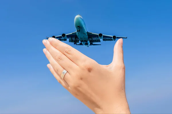 Mão feminina com um anel com um avião desenhado segurando um avião voando no céu. Viajando em um conceito de avião. Espaço de texto. Paraíso impressionante. Praia quente Mai Khao. Paisagem incrível FORMATO VERTICAL — Fotografia de Stock