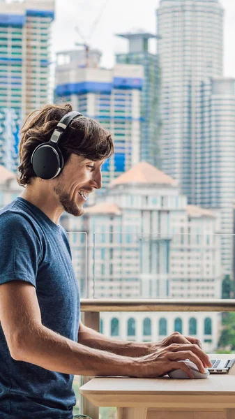 Jonge man leert een vreemde taal of leert een vreemde taal op het Internet op haar balkon tegen de achtergrond van een grote stad. Online taalschool Lifestyle verticaal formaat voor Instagram — Stockfoto