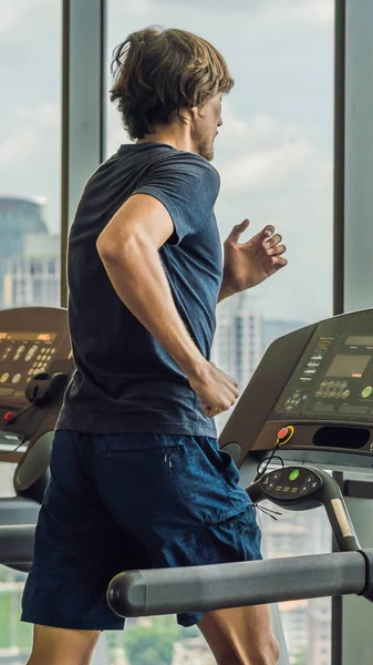 Man running in a gym on a treadmill against the background of a big city. concept for exercising, fitness and healthy lifestyle VERTICAL FORMAT for Instagram mobile story or stories size. Mobile — Stock Photo, Image