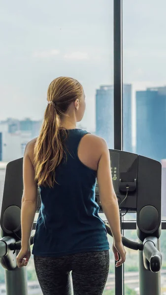sport, fitness, lifestyle, technology and people concept - woman exercising on treadmill in gym against the background of a big city VERTICAL FORMAT for Instagram mobile story or stories size. Mobile