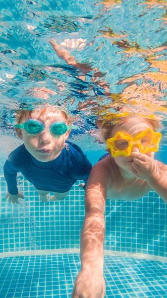 Close-up retrato subaquático das duas crianças sorridentes bonito FORMATO VERTICAL para Instagram história móvel ou tamanho de histórias. Papel de parede móvel — Fotografia de Stock