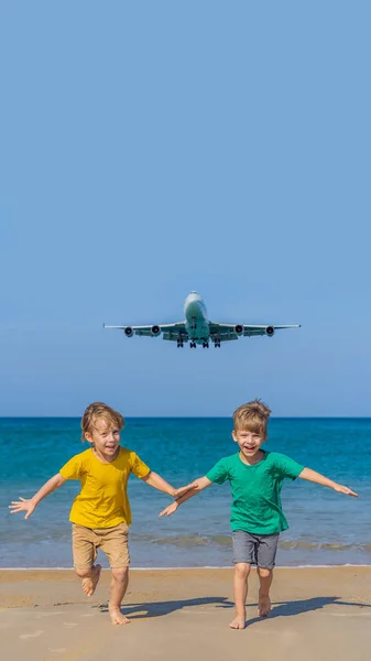 Dos chicos felices se divierten en la playa viendo los aviones de aterrizaje. Viajar en un avión con concepto de niños. Espacio de texto. Island Phuket en Tailandia. Impresionante paraíso. Playa caliente Mai Khao. Increíble. — Foto de Stock