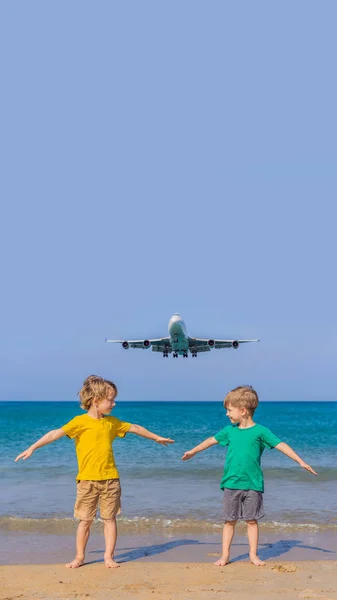 Dos chicos felices se divierten en la playa viendo los aviones de aterrizaje. Viajar en un avión con concepto de niños. Espacio de texto. Island Phuket en Tailandia. Impresionante paraíso. Playa caliente Mai Khao. Increíble. — Foto de Stock