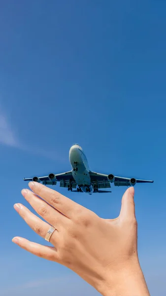 Mão feminina com um anel com um avião desenhado segurando um avião voando no céu. Viajando em um conceito de avião. Espaço de texto. Paraíso impressionante. Praia quente Mai Khao. Paisagem incrível FORMATO VERTICAL — Fotografia de Stock