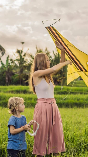 Moeder en zoon lanceren een vlieger in een veld van de rijst in Ubud, Bali eiland, Indonesië verticale indeling voor mobiele verhaal Instagram of verhalen grootte. Mobiele achtergronden — Stockfoto