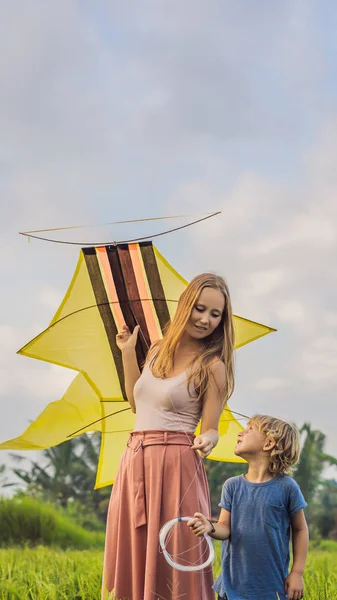 Mom and son launch a kite in a rice field in Ubud, Bali Island, Indonesia VERTICAL FORMAT for Instagram mobile story or stories size. Mobile wallpaper