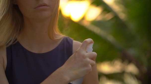 Superslowmotion tiro de uma bela jovem mulher aplicando um spray repelente antimosquito em sua pele. Um fundo tropical. Conceito de defesa de mosquitos — Vídeo de Stock