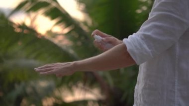 Genç bir adamın derisinde bir ANTIMOSQUITO kovucu sprey uygulama Superslowmotion atış. Tropikal bir arka plan. Sivrisinek savunma kavramı
