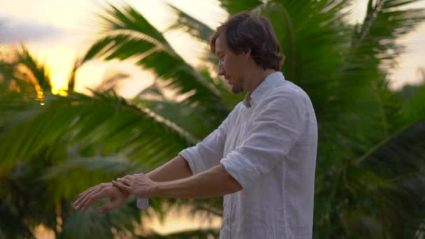 Superslowmotion disparo de un hombre joven aplicando un spray repelente antimosquitos en su piel. Un fondo tropical. Concepto de defensa de mosquitos — Vídeos de Stock