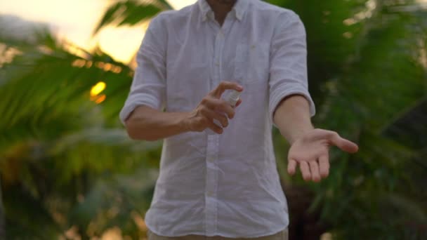 Superslowmotion scatto di un giovane che applica uno spray antizanzare repellente sulla pelle. Uno sfondo tropicale. Concetto di difesa della zanzara — Video Stock