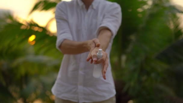 Superzeitlupenaufnahme eines jungen Mannes, der ein antimosquito-abweisendes Spray auf seine Haut aufträgt. einen tropischen Hintergrund. Mückenabwehrkonzept — Stockvideo