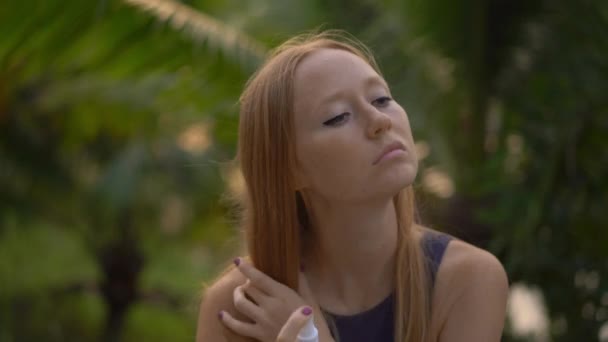 Primer plano de una hermosa mujer joven aplicando un spray repelente a los mosquitos en su piel. Un fondo tropical. Concepto de defensa de mosquitos — Vídeo de stock