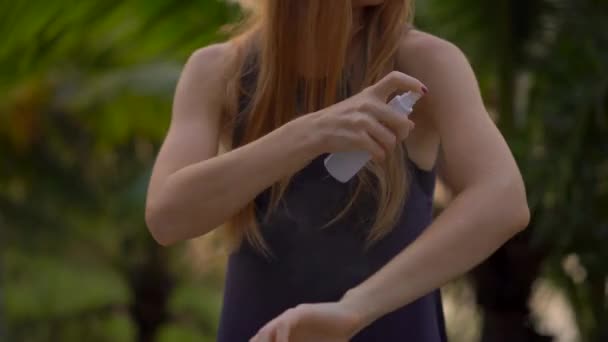 Primer plano de una hermosa mujer joven aplicando un spray repelente a los mosquitos en su piel. Un fondo tropical. Concepto de defensa de mosquitos — Vídeo de stock