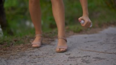 Güzel bir genç kadının bir ANTIMOSQUITO kovucu sprey derisinin üzerinde uygulama closeup çekim. Tropikal bir arka plan. Sivrisinek savunma kavramı