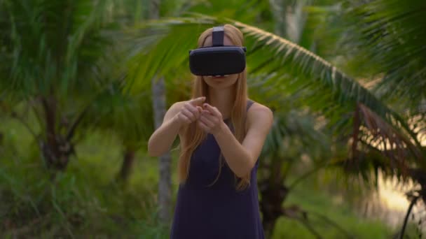 Closeup πλάνο του μια όμορφη νεαρή γυναίκα, χρησιμοποιήστε μια συσκευή VR σε ένα τροπικό πάρκο. Ένα άτομο που φορώντας ένα vr γυαλιά αισθάνεται σαν να είναι σε τροπικές περιοχές. Έννοια της επαυξημένης πραγματικότητας — Αρχείο Βίντεο
