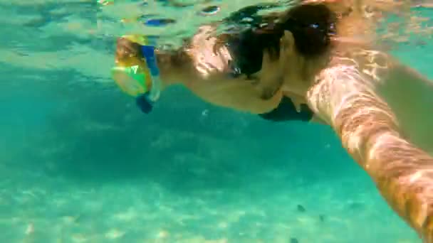 4k tiro subaquático de um menino bonito e seu pai snorkeling com máscaras e tubos em um mar tropical com muitos peixes tropicais em torno deles — Vídeo de Stock