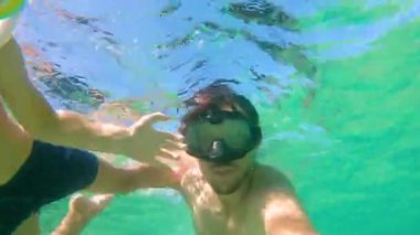 4 k Sualtı çekim küçük şirin bir çocuk ve babası bir maske ile şnorkel ve tropikal deniz ile lots-in tropikal balıklar onları çevreleyen tüplerde