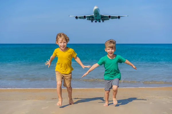 Due ragazzi felici si divertono sulla spiaggia a guardare gli aerei di atterraggio. Viaggiare su un aereo con il concetto di bambini. Spazio di testo. Island Phuket in Thailandia. Un paradiso impressionante. Spiaggia calda Mai Khao. Incredibile. — Foto Stock