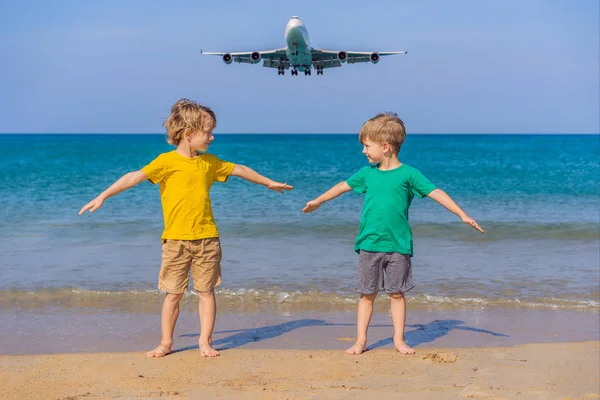 Due ragazzi felici si divertono sulla spiaggia a guardare gli aerei di atterraggio. Viaggiare su un aereo con il concetto di bambini. Spazio di testo. Island Phuket in Thailandia. Un paradiso impressionante. Spiaggia calda Mai Khao. Incredibile. — Foto Stock