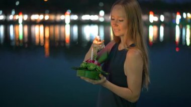 Güzel bir genç kadın Slowmotion çekim bir mum elinde bir Krathong tutarak Tayland bir Loi Krathong tatil kutluyor ışıkları