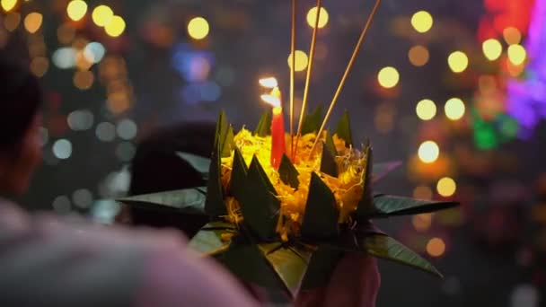 Fotografía en cámara lenta de una persona sosteniendo un krathong con una vela encendida en sus manos. Celebrando una fiesta tradicional tailandesa - Loy Krathong — Vídeos de Stock