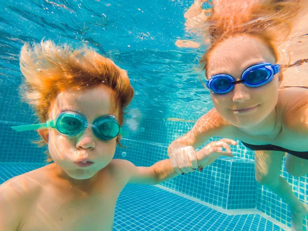 Niño aprendiendo a nadar en una piscina, madre sosteniendo al niño — Foto de Stock