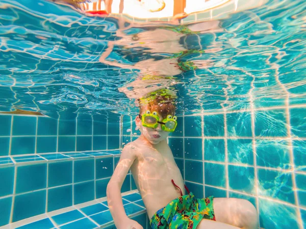 Підводний молодий хлопчик розважається в басейні з окулярами. Літні канікули розваги — стокове фото