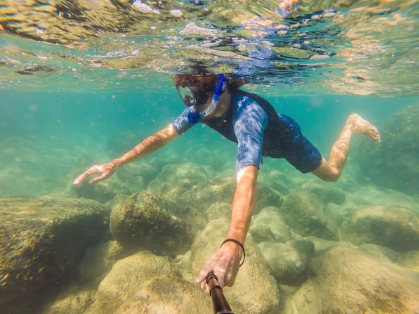 若い男性は、カラフルな魚や海洋生物との深い青色の海で水中サンゴ礁の風景の背景を探索シュノーケリング — ストック写真