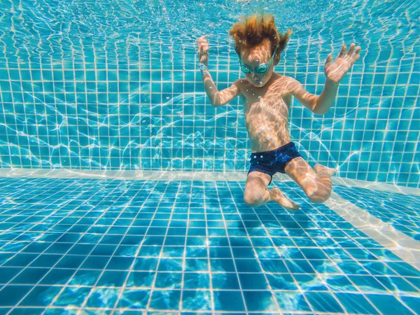 Подводный мальчик весело в бассейне с очками. Летние каникулы — стоковое фото