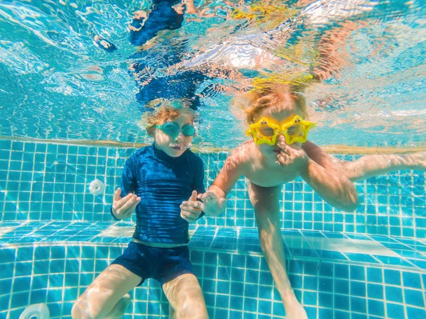 Niños divirtiéndose jugando bajo el agua en la piscina en las vacaciones de verano — Foto de Stock