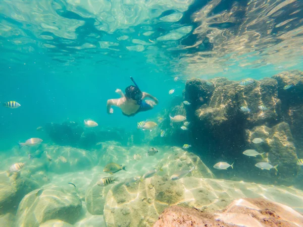 Mladí muži se šnorchlováním prozkoumají pod vodou korálový útes v hlubokém modrém oceánu s pestrými rybami a mořským životem — Stock fotografie