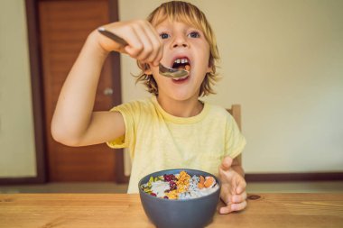 Oturma ve mango, dragon meyve, granola ve chia tohumu ile taze yüzlü kase yemek mutlu çocuk