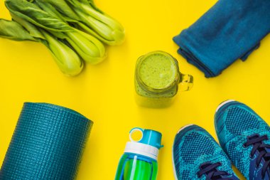 Spor turkuaz, sarı bir arka plan ve ıspanak smoothies üzerinde mavi tonları için her şey. Yoga mat, spor ayakkabı spor giyim ve su şişesi. Kavram sağlıklı yaşam tarzı, spor ve diyet. Spor