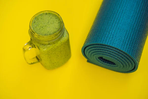 Tout pour les sports turquoise, les nuances bleues sur fond jaune et les smoothies aux épinards. Tapis de yoga, chaussures de sport vêtements de sport et bouteille d'eau. Concept mode de vie sain, sport et alimentation. Le sport — Photo