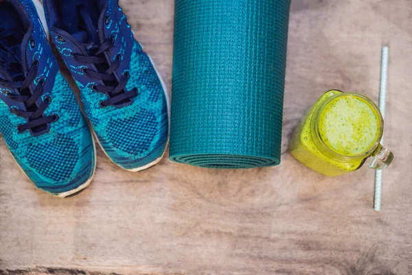 Tout pour les sports turquoise, les nuances bleues sur fond bois et les smoothies aux épinards. Tapis de yoga, chaussures de sport vêtements de sport et bouteille d'eau. Concept mode de vie sain, sport et alimentation. Le sport — Photo