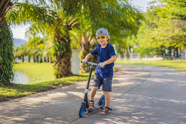 Kind auf Tretroller im Park. Kinder lernen Rollschuhlaufen. kleiner Junge beim Schlittschuhlaufen an einem sonnigen Sommertag. Aktivitäten im Freien für Kinder auf sicheren Wohnstraßen. Aktivsport für Vorschulkinder — Stockfoto