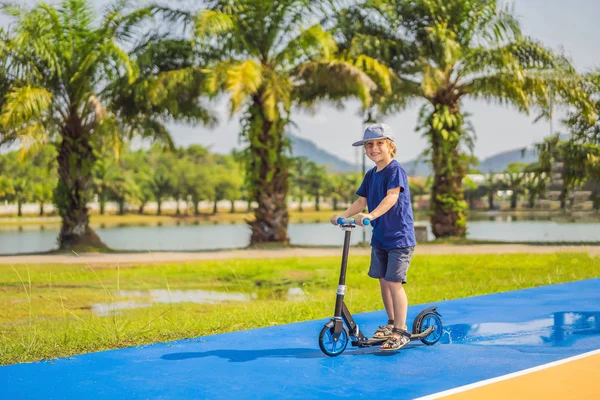 Happy child on kick scooter in on the basketball court. Kids learn to skate roller board. Little boy skating on sunny summer day. Outdoor activity for children on safe residential street. Active sport — Stock Photo, Image