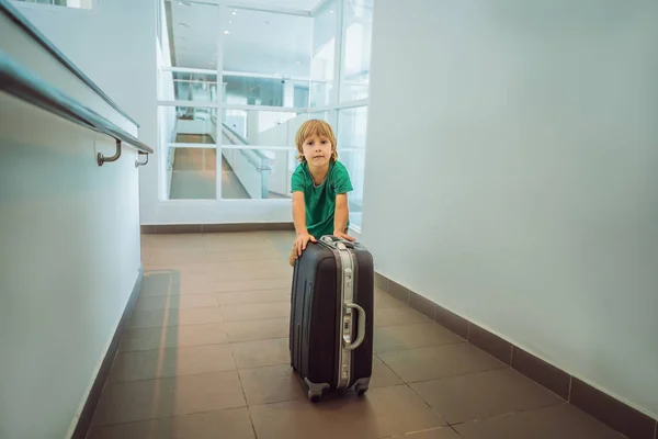 Lustiger kleiner Junge auf Urlaubsreise mit Koffer am Flughafen, drinnen — Stockfoto