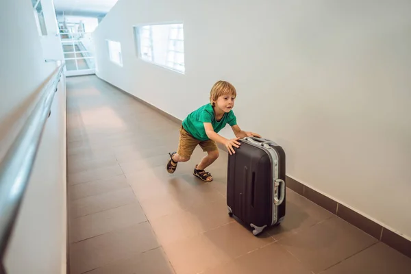 Lustiger kleiner Junge auf Urlaubsreise mit Koffer am Flughafen, drinnen — Stockfoto