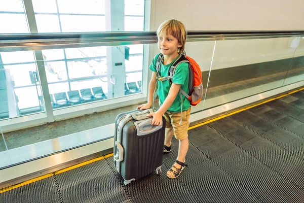 Lustiger kleiner Junge auf Urlaubsreise mit Koffer am Flughafen, drinnen — Stockfoto