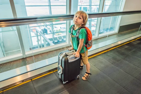 Lustiger kleiner Junge auf Urlaubsreise mit Koffer am Flughafen, drinnen — Stockfoto