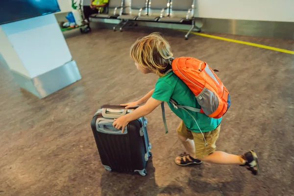 Engraçado menino indo de férias viagem com mala no aeroporto, dentro de casa — Fotografia de Stock