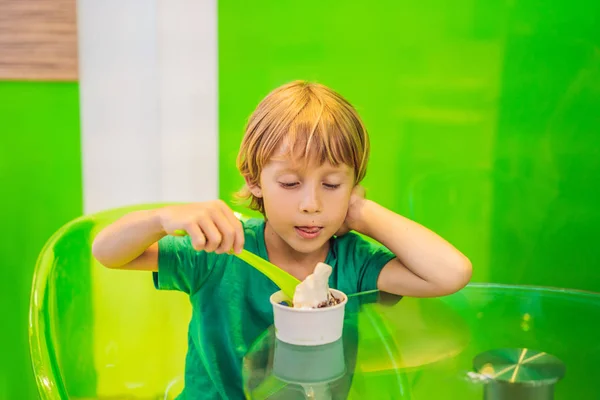 Lezzetli bir dondurma veya dondurulmuş yoğurt yiyen mutlu genç çocuk — Stok fotoğraf