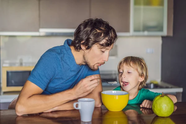 Отец и сын разговаривают и улыбаются во время завтрака на кухне — стоковое фото