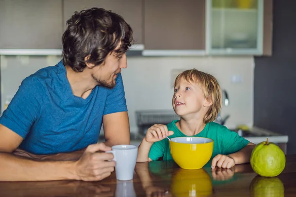 Батько і син розмовляють і посміхаються під час сніданку на кухні — стокове фото
