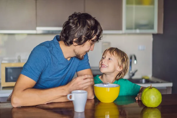 Vater und Sohn reden und lächeln beim Frühstück in der Küche lizenzfreie Stockbilder