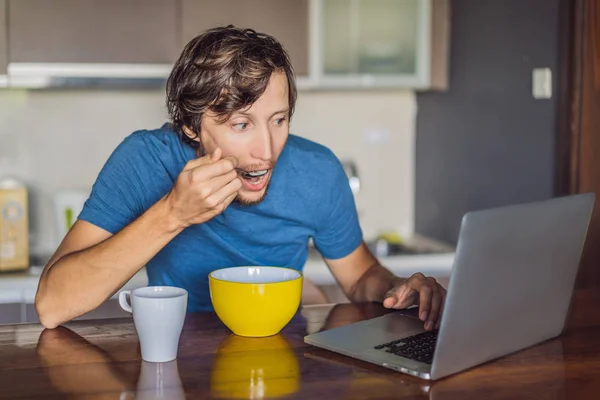 Молодий чоловік снідає і використовує ноутбук на кухні — стокове фото