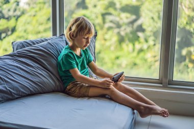 Küçük sarışın çocuk akıllı telefonda oyun oynuyor