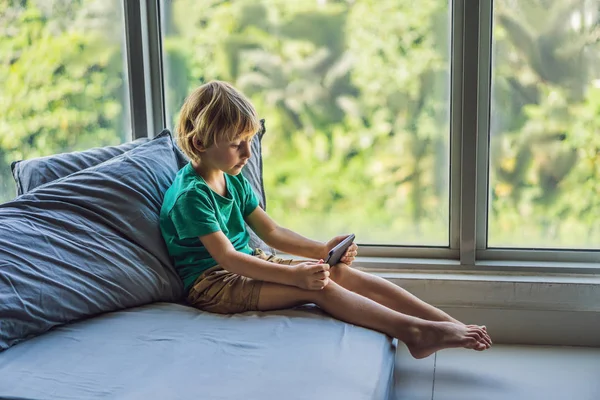 Kleiner blonder Junge spielt Spiele auf dem Smartphone — Stockfoto